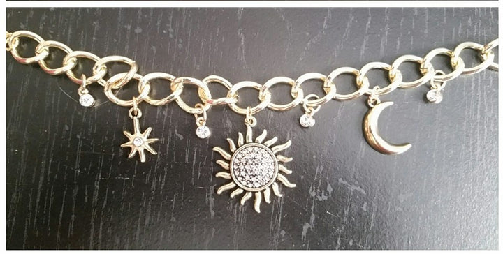 A gold charm bracelet with a star moon and a sun charm. 