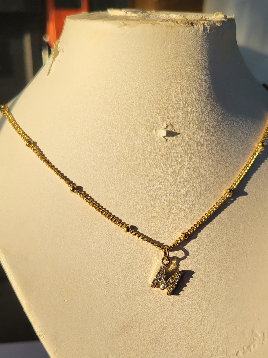 Gold necklace on a white stand with a blurred background