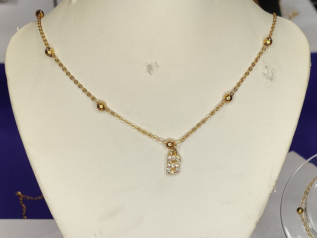 Gold necklaces on mannequin and clear stands against a purple background