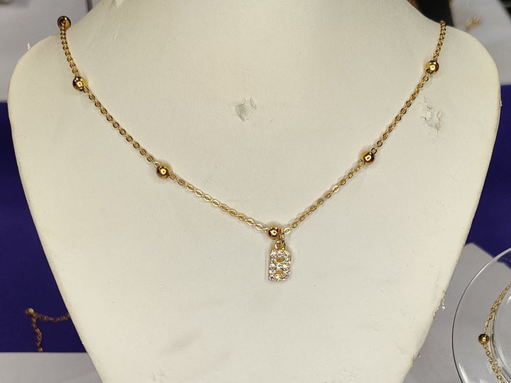 Gold necklaces on mannequin and clear stands against a purple background